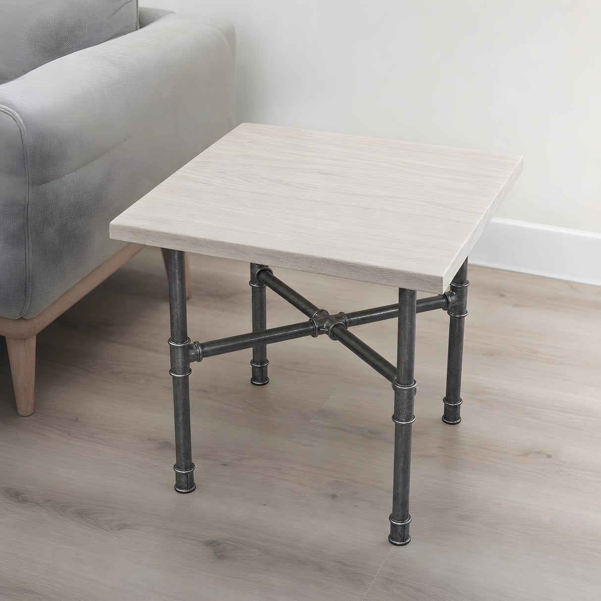 Piètement de table basse en croix, fonte et acier vernis Ø 27 mm, en situation sous un plateau en frêne blanchi