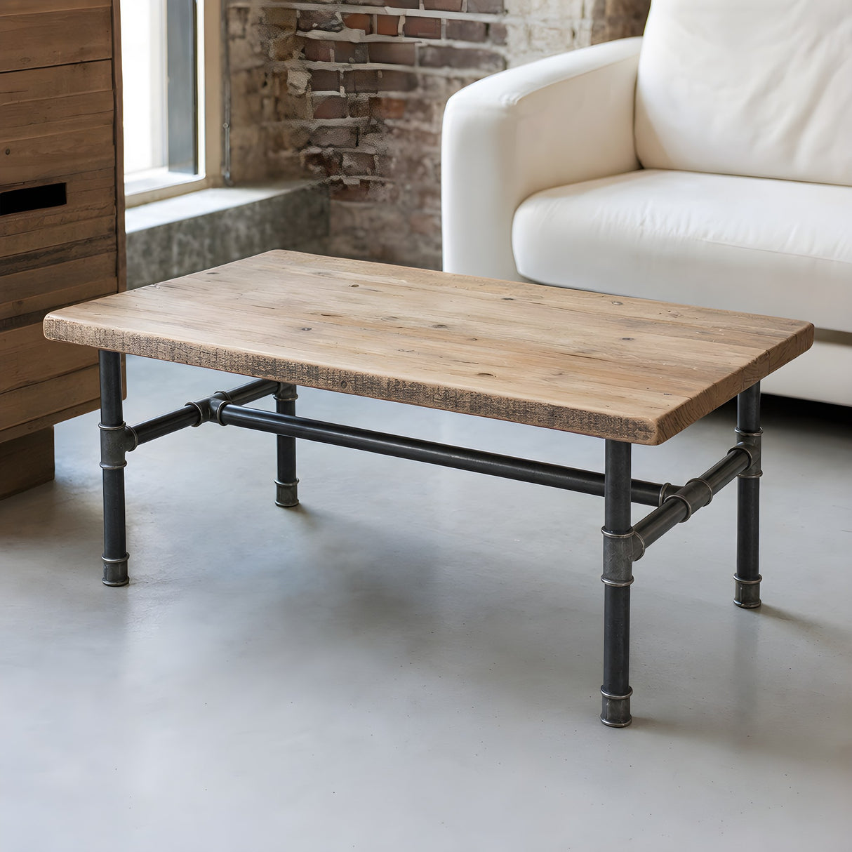 Piètement de table basse en H, fonte et acier vernis Ø 34 mm, en situation sous un plateau en pin de récupération