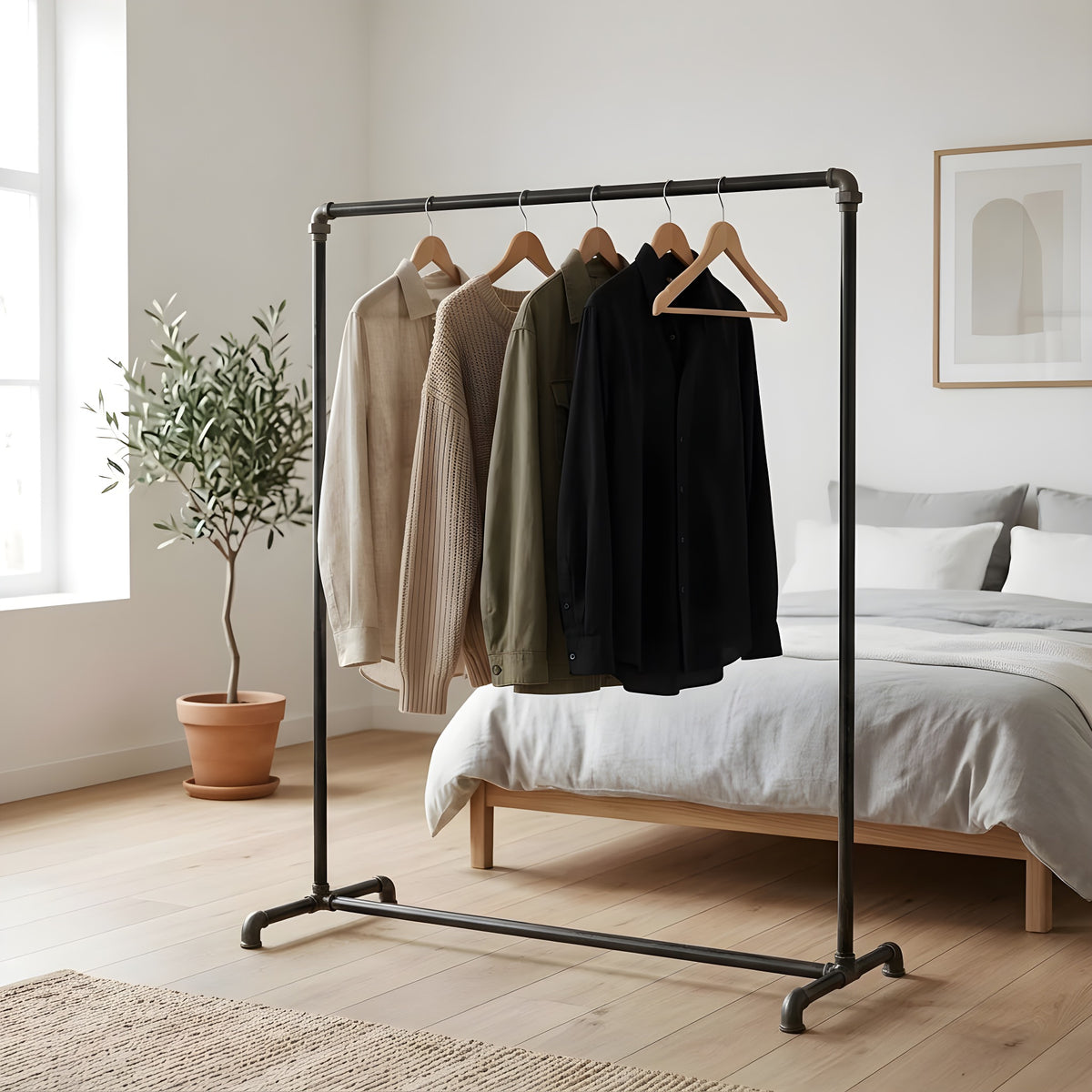 Portant à vêtements industriel en tubes de plomberie noirs dans une chambre lumineuse, vêtements sur cintres en bois