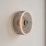 Ampoule LED donut E27 en verre fumé Ø 195 mm allumée en applique murale sur un mur clair épuré
