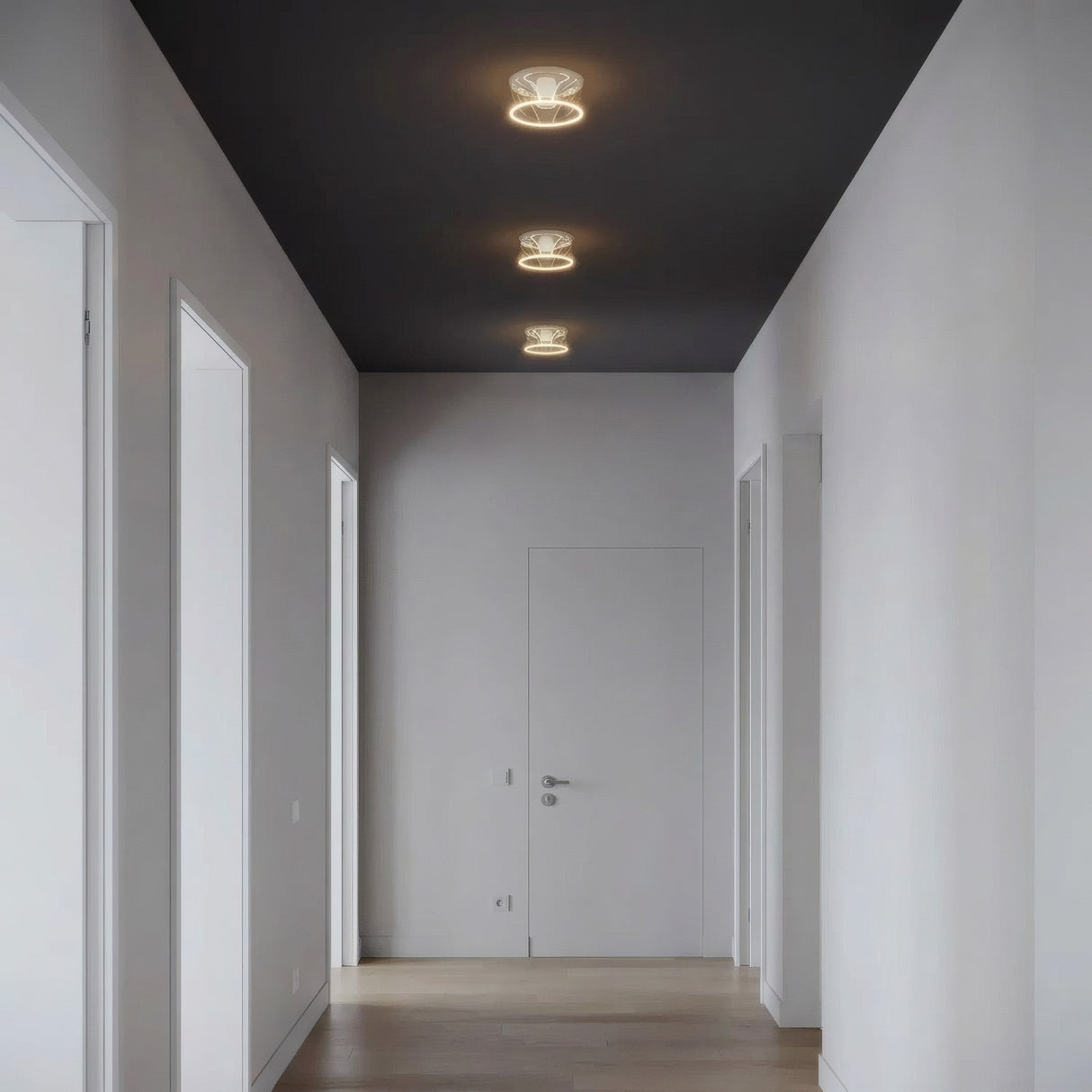 Trois ampoules LED donut E27 en verre transparent alignées au plafond d'un couloir épuré