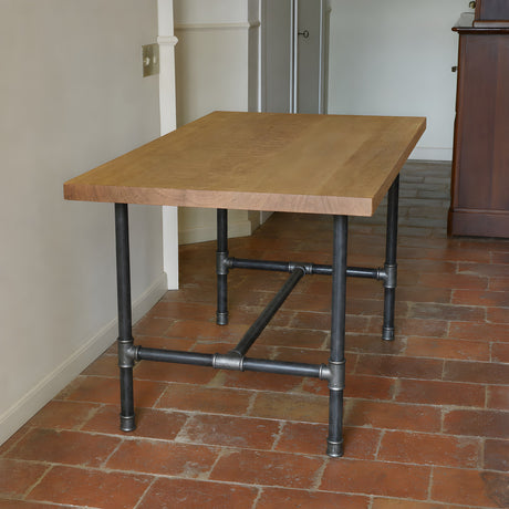 Piètement de table à manger en H, fonte et acier vernis Ø 34 mm, en situation sous un plateau en chêne brut de sciage
