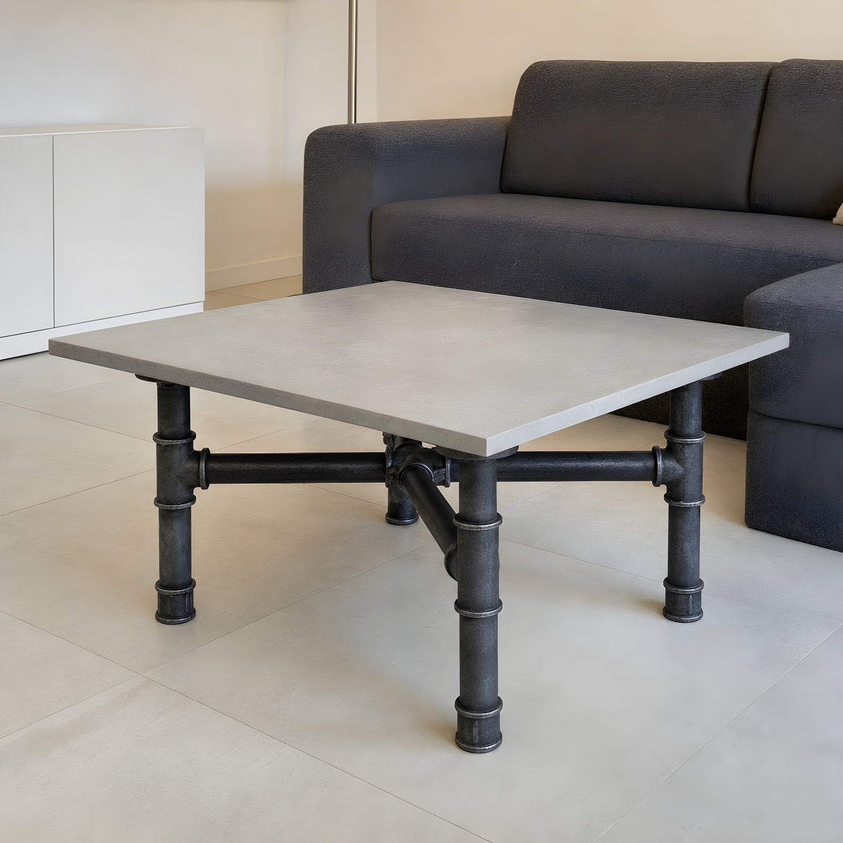 Piètement de table basse en croix, fonte et acier vernis Ø 42 mm, en situation sous un plateau en béton clair poli