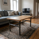 Piètement de table basse en H, fonte et acier vernis Ø 34 mm, en situation sous un plateau en chêne massif clair