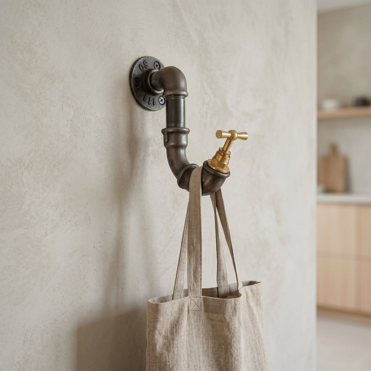 Patère robinet fonte et laiton sur mur microciment, sac en lin suspendu, déco minimaliste