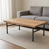 Table basse industrielle avec plateau en chêne clair sur piètement fonte en H, mise en situation (plateau non fourni)